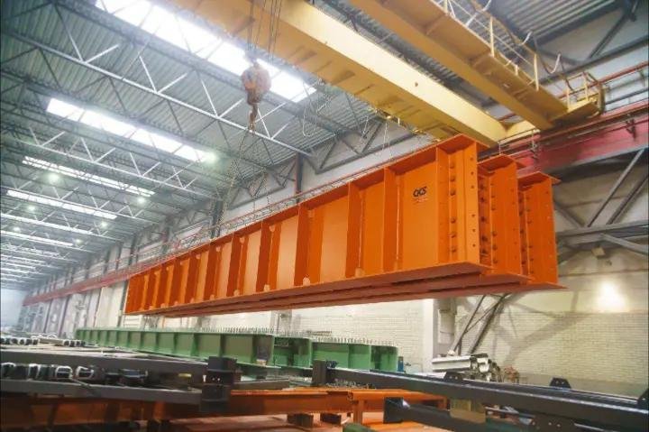Grindă metalică portocalie ridicată în hala de producție